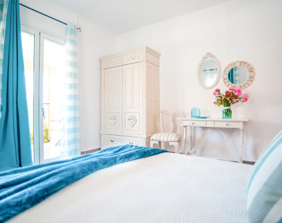 A spacious double bedroom featuring an indoor sitting area and a scenic view of the garden.